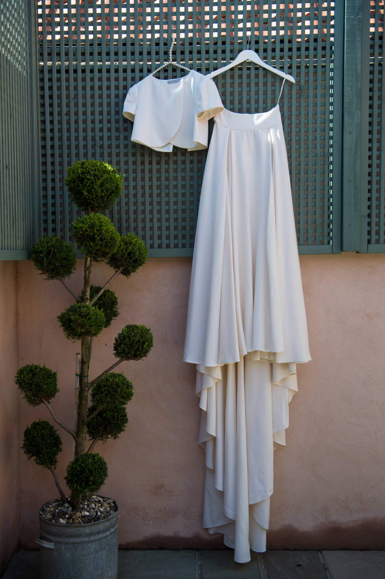 An elizabeth stuart wedding gown hanging up in a pretty mediterranean garden